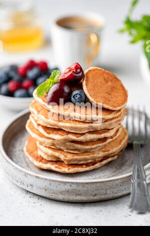 Frittelle di avena vegana con frutti di bosco su piatto. Frittelle senza glutine Foto Stock