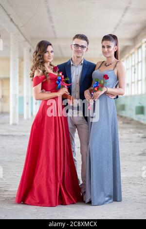 Bel ragazzo in abito blu con due belle ragazze in abiti glamour. Pronti per la loro notte di pom Foto Stock