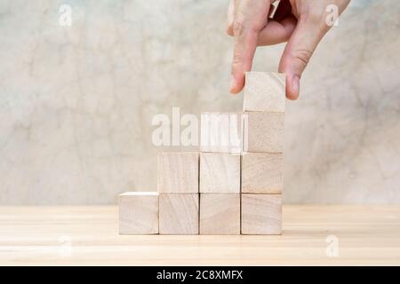 Disposizione manuale di blocco di legno impilato come scala su tavolo di legno. Concetto aziendale per il processo di successo della crescita. Spazio di copia Foto Stock