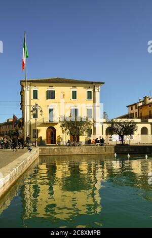 Facciata del municipio della città vecchia sulla riva del lago di Garda con bandiera italiana in una giornata di sole, Lazise, Verona, Veneto, Italia Foto Stock