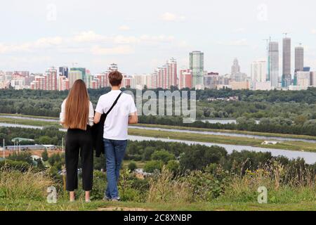 Giovane coppia innamorato in cima a una collina sullo sfondo di una città. Estate tempo libero ed escursioni, data romantica, concetto di pianificazione futura Foto Stock