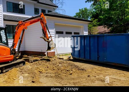 Mini escavatore e bobina in cantiere per la lavorazione di cassonetti per la costruzione di contenitori di rifiuti Foto Stock