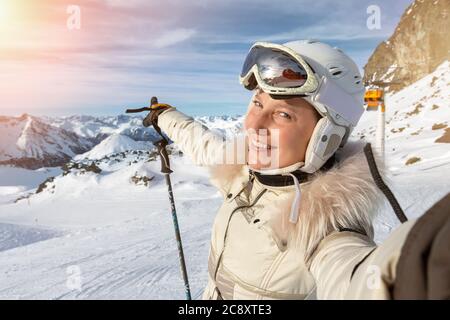 Giovane adulto bello felice attraente caucasico sorridente sciatore ritratto donna facendo selfie sulla cima della montagna mostrando panorama stazione sciistica Foto Stock