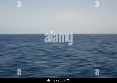 Onde di mare profondo e cielo blu. Sfondo sfocato con movimento astratto. Foto Stock