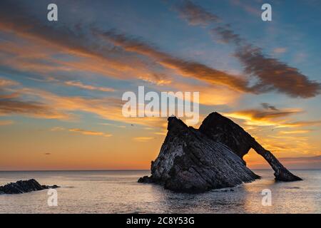 ARCO FIDDLE ROCK PORTKNOCKIE MORAY COSTA SCOZIA UN'ALBA DI LUGLIO CON UNA GAMMA DI NUVOLE DI COLORE ARANCIONE SULLA ROCCIA E SUL MARE Foto Stock