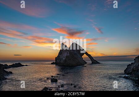 ARCO FIODLE ROCK PORTKNOCKIE MORAY COAST SCOZIA LUGLIO ALL'ALBA CON UNA GAMMA DI NUVOLE ROSA SULLA ROCCIA E SUL MARE Foto Stock