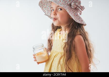 Bella bambina con cucchiaio in bocca mangiare gustosa crema. Mangiare gelato è divertente Foto Stock