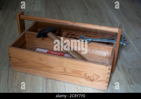 Cassetta portautensili in legno antico con manico e utensili su fondo in legno Foto Stock