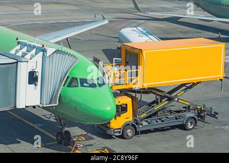 Camion giallo accanto a un aereo passeggeri, servizio di prevolo aeroporto Foto Stock