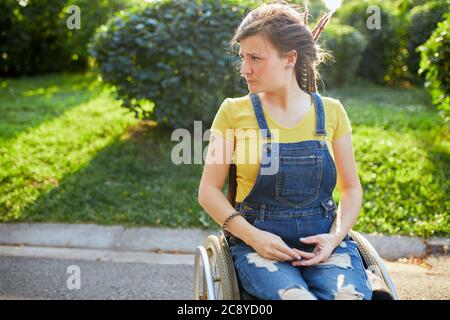 giovane bella donna non valida con elegante capelli seduti sulla sedia a rotelle che guarda via. primo piano ritratto, copia sace, tempo libero, tempo libero, tempo libero Foto Stock