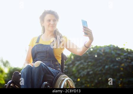 sorridente bella ragazza disabili positiva che si pone alla fotocamera. primo piano ritratto. telefono dipendenza. copia spazio Foto Stock