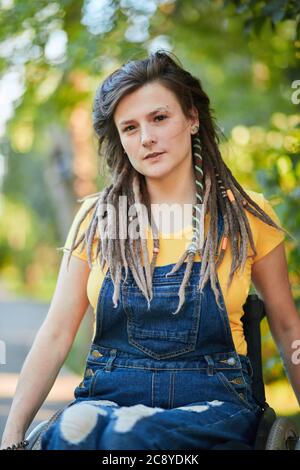 Bella giovane donna in generale e T-shirt gialla che riposa nella foresta. Primo piano ritratto. Stile di vita concetto Foto Stock