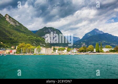 Riva del Garda porto con barche situato presso il lago di Garda, alte montagne sullo sfondo, giornata di sole Foto Stock