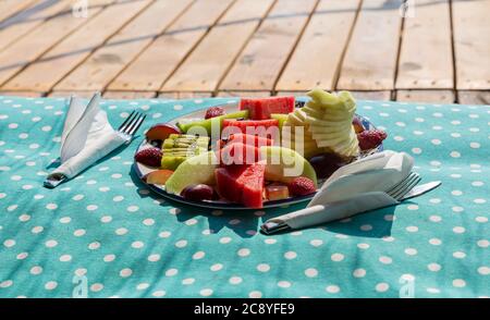 Ciotola di sana Macedonia di frutta fresca su cuscino e sfondo di legno Foto Stock