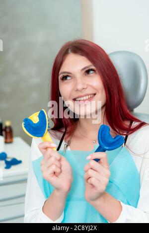 Una ragazza dimostra il risultato di getti dei suoi denti su un cucchiaio con materiale siliconico Foto Stock