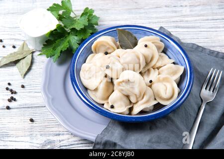 Pelmeni tradizionali, ravioli, gnocchi ripieni di carne su sfondo ligneo, cucina russa Foto Stock