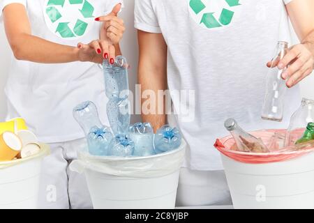 i volontari mettono gli oggetti che possono essere riciclati nei contenitori corretti. primo piano ritratto, studio shot, coppia scegliendo plastica e vetro per metterli int Foto Stock