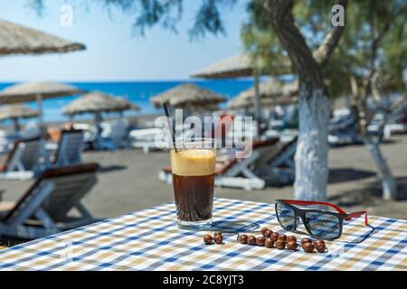 Bicchiere di cocktail rinfrescante sul tavolo del caffè sullo sfondo della spiaggia Foto Stock