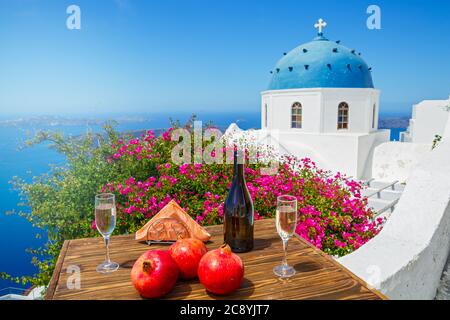 Vino e melograno per due sullo sfondo del mare e l'isola di Santorini. Foto Stock