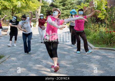 Indossando maschere e osservando la distanza, un gruppo di donne cinesi americane pratica la danza cinese moderna. A Flushing, Queens, New York City Foto Stock