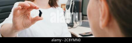 Audiologo che mostra l'apparecchio acustico BTE del paziente. Trattamento della sordità negli adulti. Clinica uditiva Foto Stock
