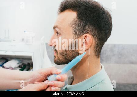 processo di stampaggio di auricolari individuali per apparecchi acustici. Un uomo, avendo procedura che fa gli auricolari individuali Foto Stock