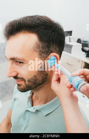 processo di stampaggio di auricolari individuali per apparecchi acustici. Un uomo, avendo procedura che fa gli auricolari individuali Foto Stock