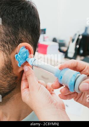 processo di stampaggio di auricolari individuali per apparecchi acustici. Un uomo, con procedure che si personalizzano in base alla forma dell'orecchio individuale di una persona Foto Stock