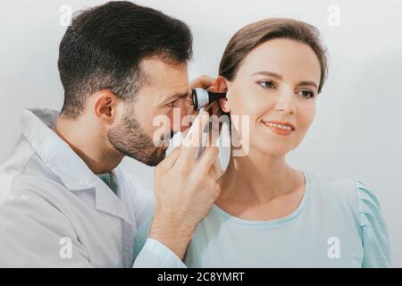 ENT medico che fa un esame dell'orecchio con un otoscopio ad una paziente di donna. Clinica uditiva Foto Stock