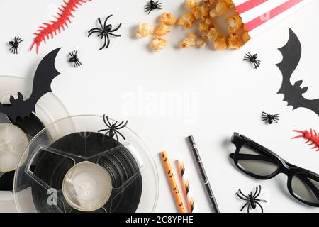 Festa notturna di Halloween, guardando film horror concetto. Composizione piatta con decorazioni halloween, popcorn, bobine, bicchieri, cannucce da bere su whit Foto Stock