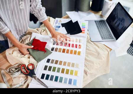 dressaker che punta al filo rosso, ha deciso di cucire un maglione rosso. primo piano vista laterale foto Foto Stock