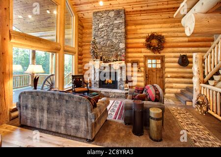 Un lussuoso soggiorno, con camino e arredi confortevoli, in una moderna cabina in legno in montagna. Foto Stock