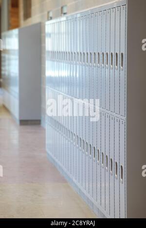 Armadietti con serrature combinate, affiancati nel corridoio di una scuola superiore, con messa a fuoco che si ripresenta nel backround. Foto Stock