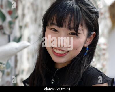 Una bella femmina giapponese sorride per la macchina fotografica al famoso tempio Wat Arun di Bangkok. Foto Stock