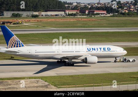 United Airlines Boeing 777-222ER (Reg N788UA) spinto indietro da un trattore rimorchiatore su una delle linee di taxi dell'aeroporto internazionale di Sao Paulo/Guarulhos. Foto Stock