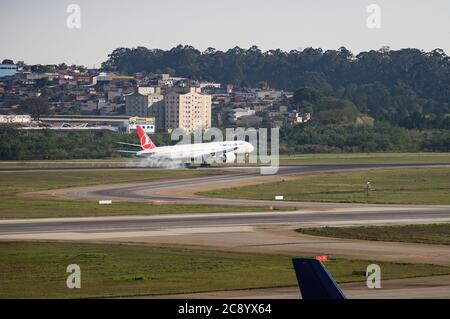 Turkish Airlines Boeing 777-3F2ER (Reg. TC-LJK) fumare i pneumatici del carrello di atterraggio mentre si tocca la pista 27L di Sao Paulo/Guarulhos Intl. Aeroporto. Foto Stock