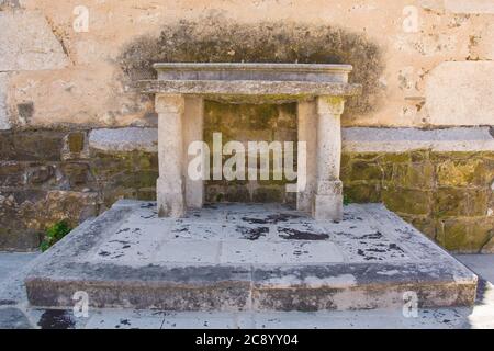 Un altare storico in pietra accanto al campanile della chiesa parrocchiale di San Vito nel villaggio di Podnanos, Valle di Vipava, comune di Vipava, Primorska, Slovenia Foto Stock