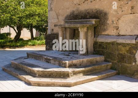 Un altare storico in pietra accanto al campanile della chiesa parrocchiale di San Vito nel villaggio di Podnanos, Valle di Vipava, comune di Vipava, Primorska, Slovenia Foto Stock