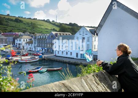 Woman Tourist guardando dalla vista elevata il panorama sul porto di Mevagissey a Cronwall, Regno Unito Foto Stock
