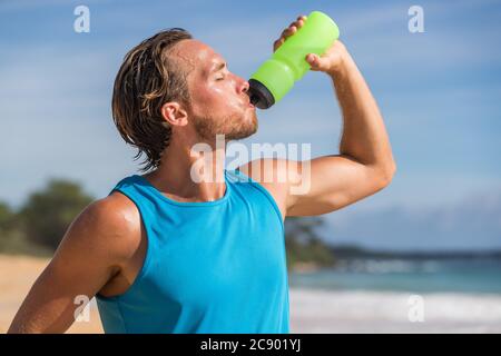 Sport bottiglia drink sport uomo acqua potabile sulla spiaggia run. Corridore maschile sudato e assetato dopo un allenamento difficile Foto Stock