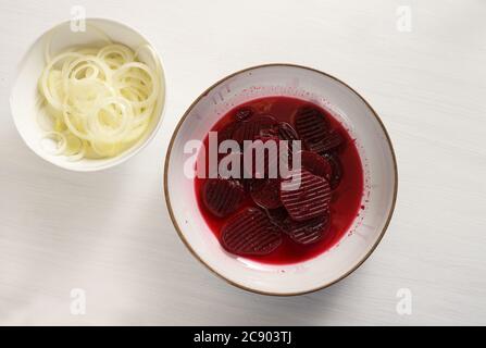 Anelli di barbabietola e cipolla cotti, ingredienti per un'insalata sana in ciotole su un tavolo bianco, spazio copia, vista dall'alto Foto Stock
