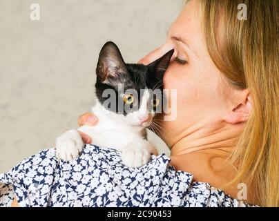 Foto di stile di vita di una donna vestita casual che sta tenendo e accarezzando e baciando carino un gatto. cat ama stare in braccia di ragazze. Messa a fuoco selettiva. Foto Stock