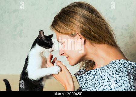 Foto di stile di vita di una donna vestita casual che sta tenendo e accarezzando e baciando carino un gatto. cat ama stare in braccia di ragazze. Messa a fuoco selettiva. Foto Stock