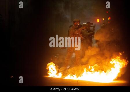 Portland, OREGON, Stati Uniti. 27 luglio 2020. Gli ufficiali federali camminano davanti a un piccolo incendio mentre disperdono una protesta contro l'ingiustizia razziale e la brutalità della polizia davanti al tribunale Mark O. Hatfield a Portland, Ore., lunedì mattina, 27 luglio 2020. Credit: Nathan Howard/ZUMA Wire/Alamy Live News Foto Stock