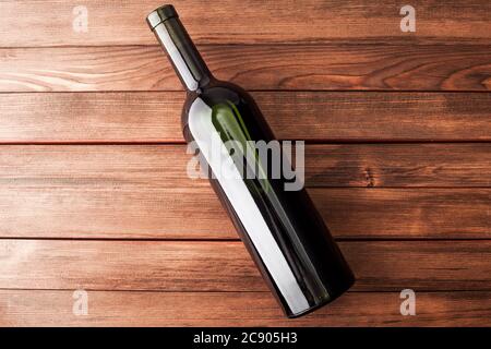 Bottiglia di vino scuro su fondo di legno, alcool d'elite in una bottiglia verde su tavole marroni. Foto Stock