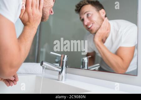 Uomo che lava il viso nel lavandino del bagno che sciacqua dopo la rasatura. Copyspace stile di vita domestico Foto Stock