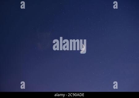 Paesaggio notturno, cielo stellato blu scuro, vista della luna luminosa (Crescent) in tempo senza nuvole. Foto su un obiettivo a fuoco lungo con strati applicati. Foto Stock