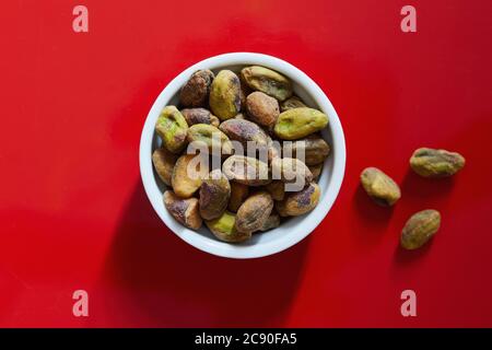 Pistacchi in ciotola su sfondo rosso Foto Stock