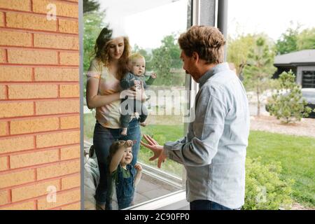 USA, Utah, Salt Lake City, il padre che visita partner e bambini (6-11 mesi, 2-3) attraverso la finestra Foto Stock