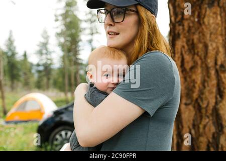 USA, Utah, Uninta Wasatch cache National Forest, Donna che tiene figlio del bambino (6-11 mesi) durante il campeggio Foto Stock